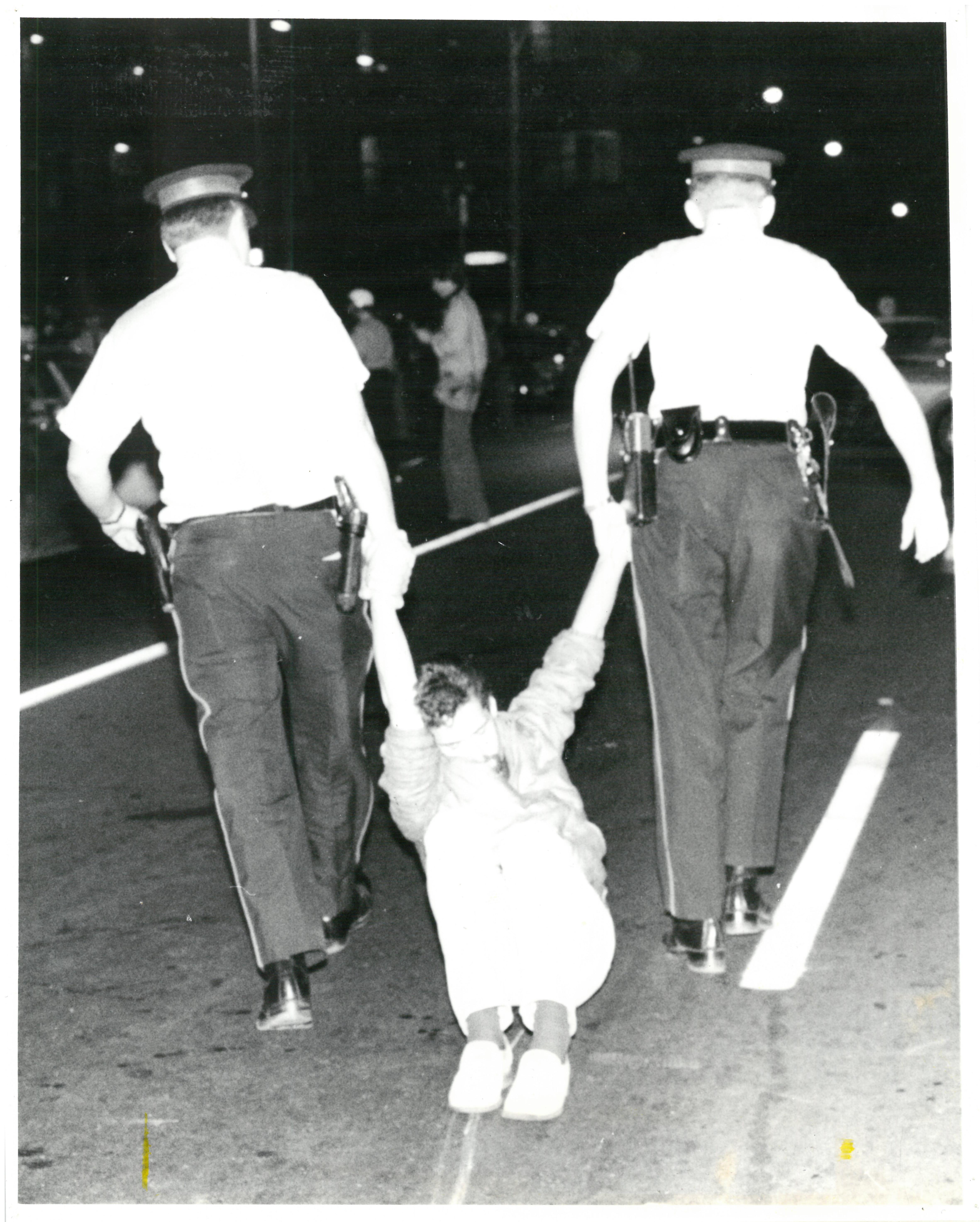 Black and white photo of police dragging someone down the street