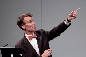 Bill Nye giving a lecture, pointing to a screen.