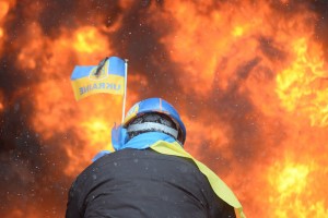 Backside view of a protester, wearing colours of the Ukrainian flag, facing a wall of flames set by protestors. Kyiv, Ukraine, January 22, 2014.