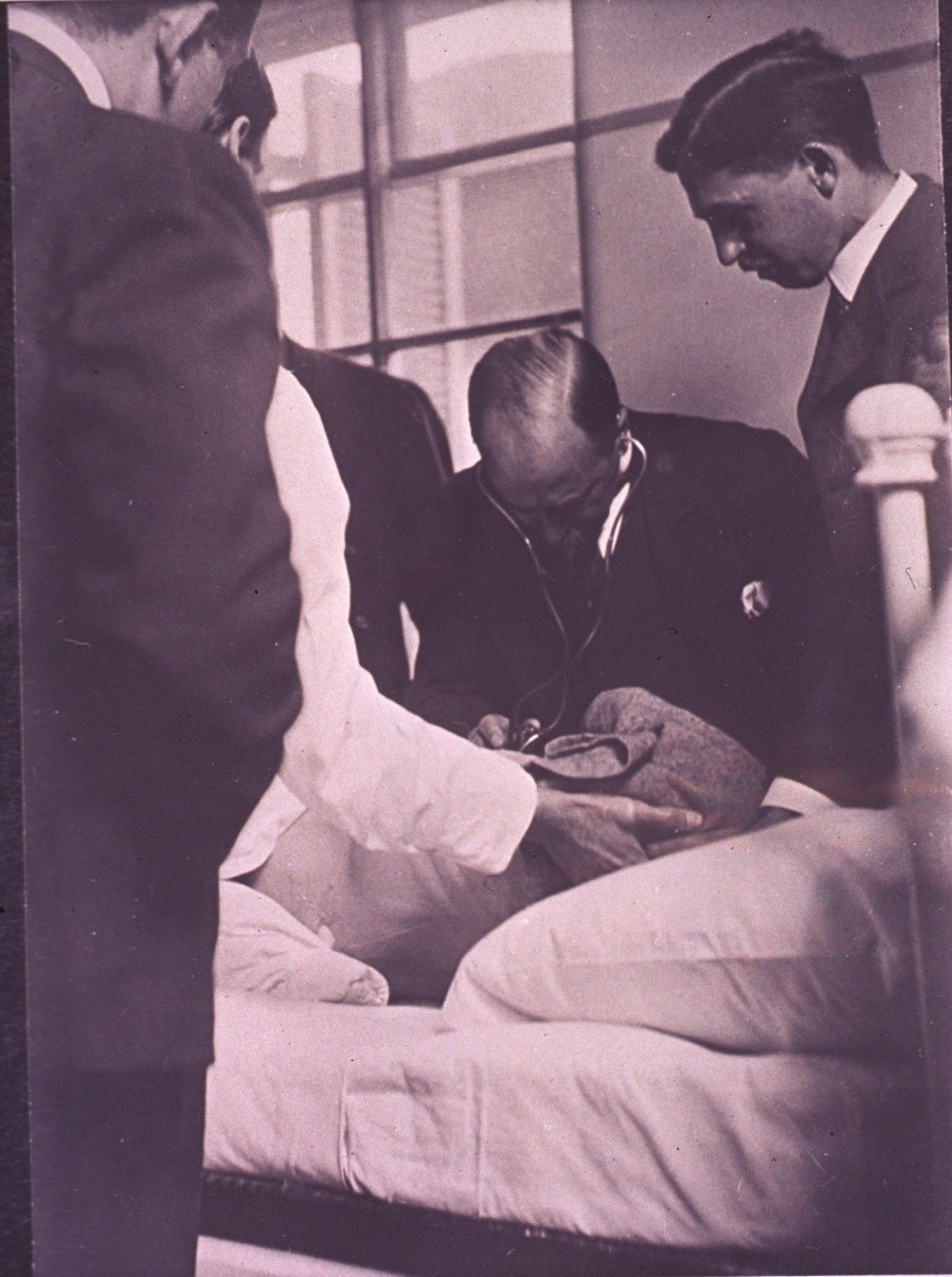 William Osler listens to a patient through a modern binaural stethoscope; medical students are gathered around during teaching at Johns Hopkins, ca. 1903. Courtesy of the National Library of Medicine.